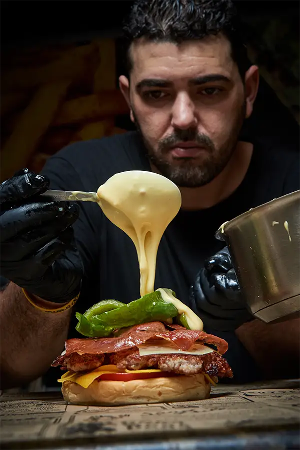 Foto de Brice Fodil Bolo echando salsa sobre una hamburguesa